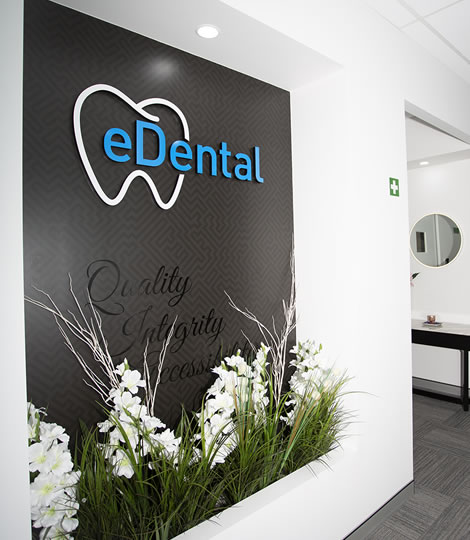 Wall with the logo of the eDental Perth with flowers and plants below it and that is considered as one of the general dentistry of eDental Perth.