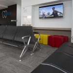 A reception area for eDental Perth patients/clients with chairs and a widescreen TV hanging on the wall.
