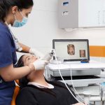 A dental nurse, wearing a uniform, is doing a dental procedure to a female patient inside eDental Perth clinic.