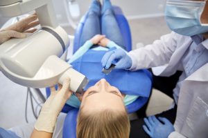Woman lying on a dental chair along with the dentist and a nurse, and as the featured image of 