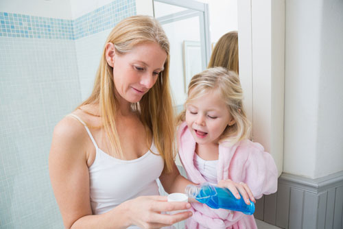 A mother and her daughter pouring a mouthwash on a small cup, and representing on the 