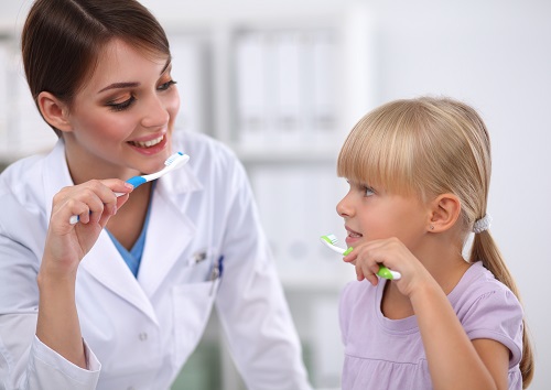 Nurse and a girl both holding a toothbrush and representing as the 