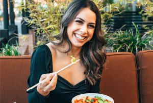 Smiling woman while eating and that represents as the header image of 
