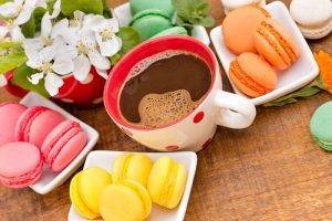 Cup of coffee placed on a table along with other sugary foods and as the header image of 