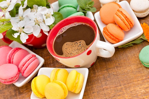 Cup of coffee placed on a table along with other sugary foods and that represents the 