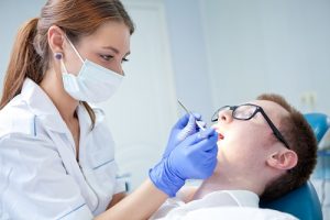 Woman dentist treating the tooth of a male patient and as the header image of 