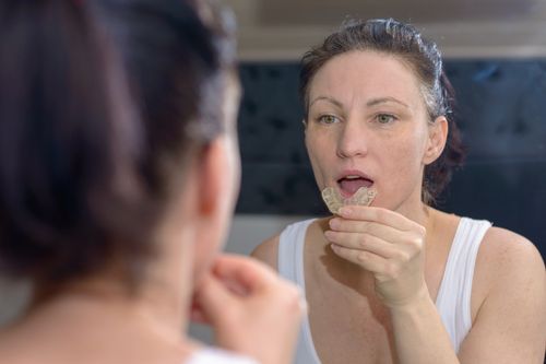 Woman putting on her mouthguard or nightguard.