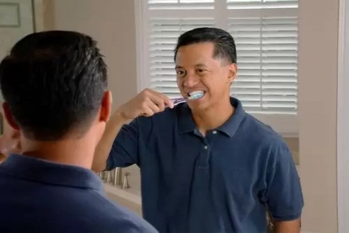 Man brushing his teeth in front of a mirror, which represents the 