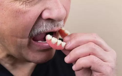A person is putting on artificial teeth, which represents the 