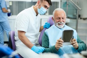 A dentist and patient looking on a mirror, which represents the 