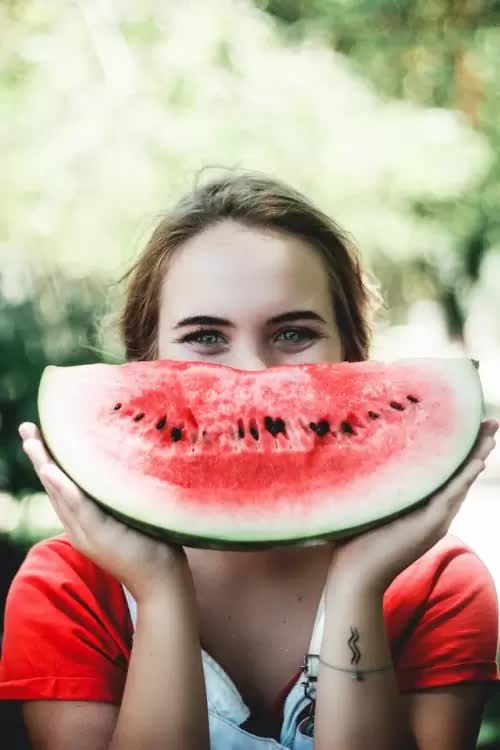 A woman smiling and holding a slice of watermelon which represents the 